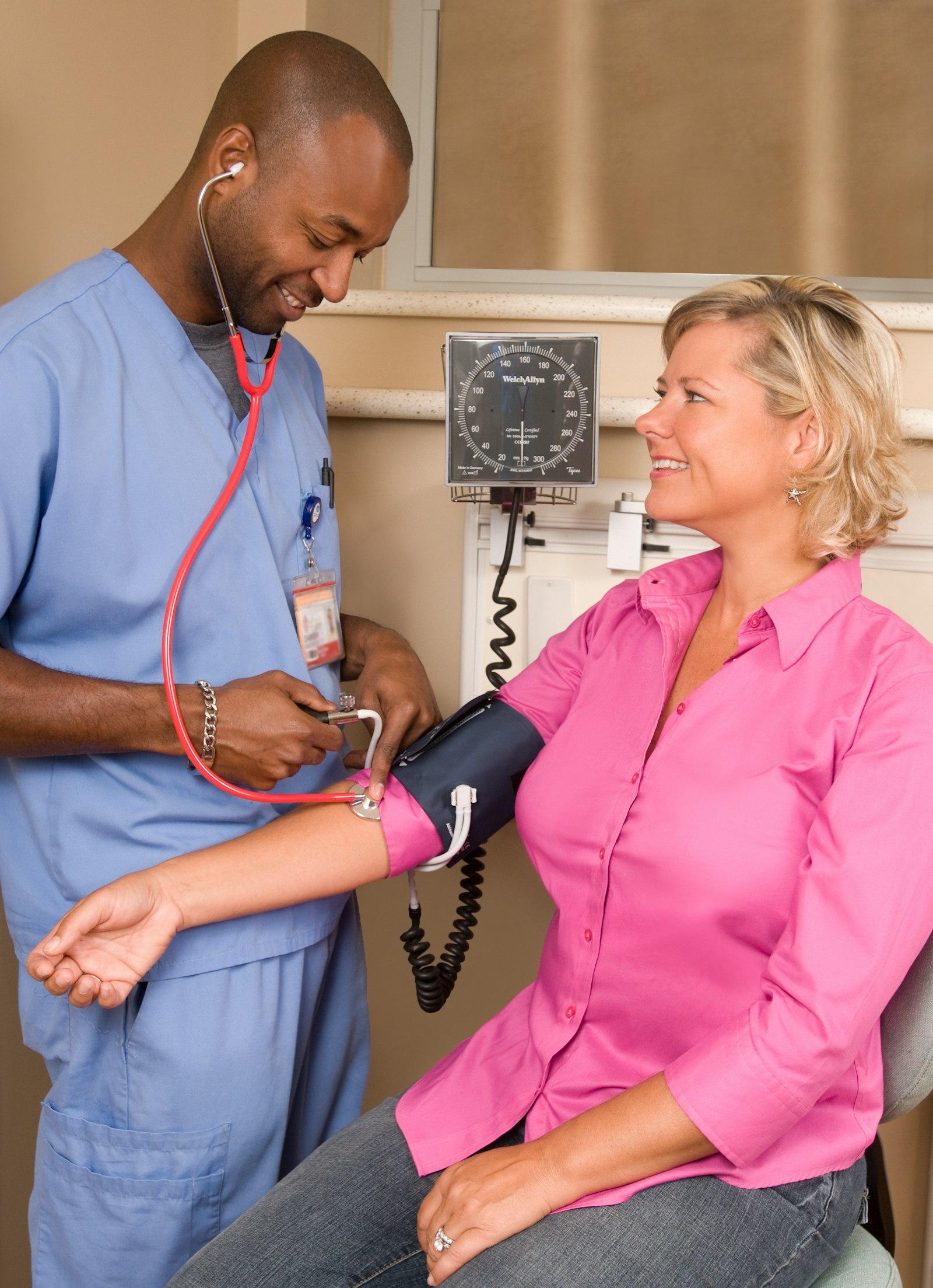 A nurse checking an elderly man's blood pressure at home.